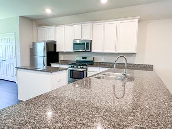 a kitchen with white cabinets and granite countertops